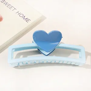 Detail of light blue rectangle hair claw clip with a dark blue heart on a white table