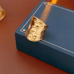 Vue détaillée d'une bague large dorée avec texture géométrique irrégulière et effet martelé