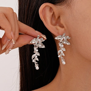 Silver flower and leaf earrings with white pearls in a long tassel drop style on model