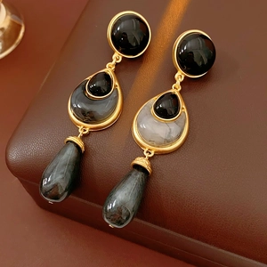 Detailed view of vintage gold floral teardrop earrings with black and grey stone inlays