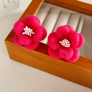 Gros plan sur les boucles d'oreilles fleurs en feutre de laine rose faites à la main