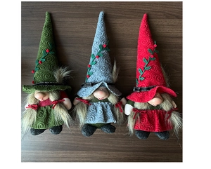 Close-up of three handmade Christmas gnomes with spiral hats and berry leaf details