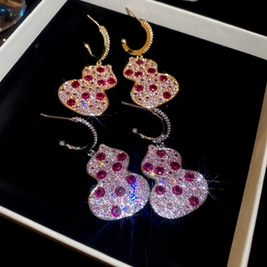 Macro detail of wulu drop earrings with pave zircons and red gemstones on velvet