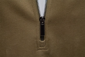 Detail of olive green knit fabric texture with high-quality black metal zipper