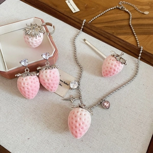 Detailed set of pink strawberry necklace and earrings with silver leaves on linen