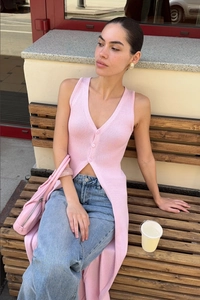 Close-up of pink slim-fit knitted vest featuring three buttons and a side slit design