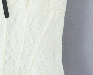 Close-up of white lace fabric texture and black ribbon bow detail on French dress