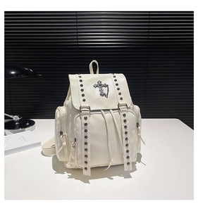 Detail of white PU leather backpack featuring silver cross pendant and rivet studs