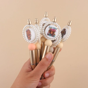 Close-up of golden beaded pens with pearl ring tops and highland cow printed patterns