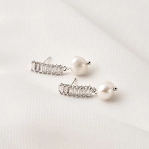 Macro shot of S925 silver earrings featuring rectangular crystals and white shell pearls