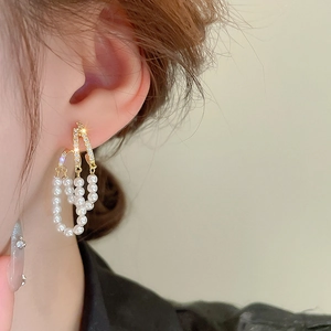 Detail of elegant gold double-layer pearl fringe earrings with sparkling zircon accents