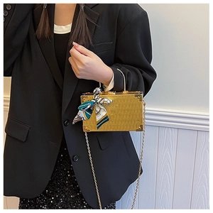 Detail of gold box clutch featuring brushed metal texture and decorative silk scarf