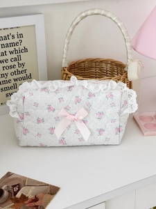 Detail of floral quilted makeup bag featuring white lace trim and a pink silk bow
