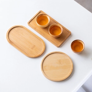 Flat lay of rectangular, oval, and round bamboo trays with white ceramic teacups