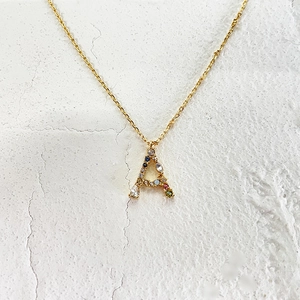 Detail of 18k gold letter A pendant with colorful zircon stones on thin chain