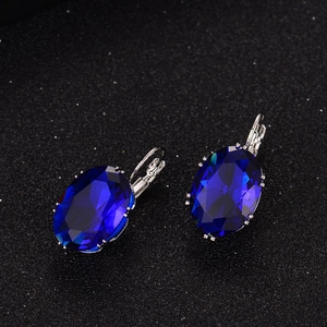 Detailed macro view of lever-back earrings with large oval blue zircon on dark texture