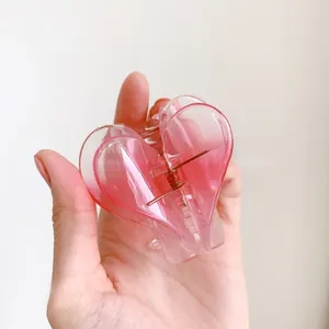 Detailed macro view of heart-shaped hair claw clip with pink gradient and metal spring