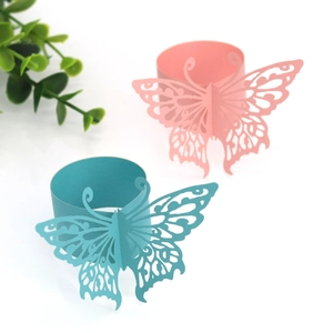 Detailed view of pink and turquoise laser-cut butterfly napkin rings on white background