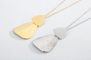Macro detail of gold and silver plated titanium steel necklaces with hammered texture pendants