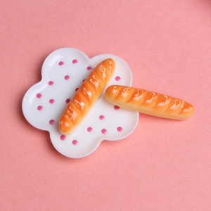 Vue détaillée de mini baguettes sur une assiette à pois pour décor de maison de poupée