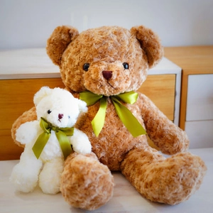 Cuddly plush teddy bear toys in brown and white colors with elegant green satin bows