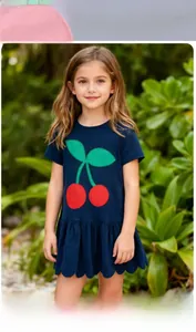 Detail of navy knit girls' dress featuring a large red cherry embroidery and ruffled hem