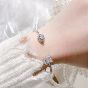 Detail of silver open bangle with pear and rectangular zircon stones on a female wrist