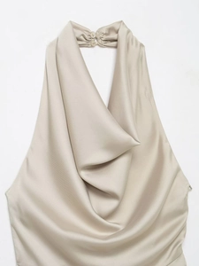 Détail du haut dos nu en satin beige élégant avec col drapé et fermeture à bouton