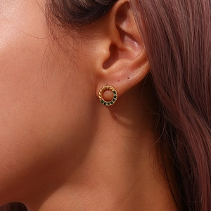 Detailed view of a gold-plated twisted hoop earring set with green cubic zirconia stones