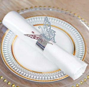 Close-up of a silver butterfly napkin ring on a white cloth on a gold-rimmed plate