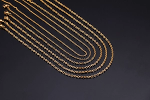 Detail of layered gold chain necklaces with lobster clasp and sleek metallic finish