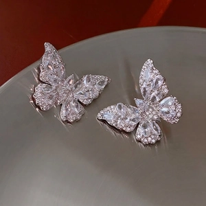 Elegant butterfly stud earrings with zircon crystals on a reflective metallic display tray
