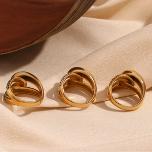 Close-up of 18K gold-plated knotted rings with green gemstone and white zircon details