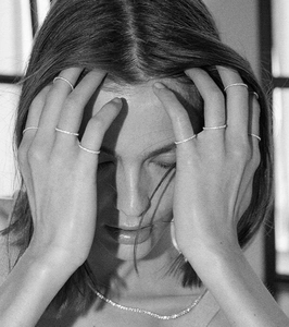 Artistic detail of minimalist sparkling diamond rings and necklace on model in black and white
