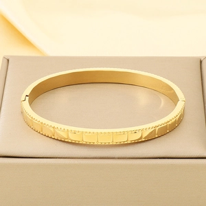Detailed close-up of a gold wave-patterned bangle with a secure hinge clasp mechanism