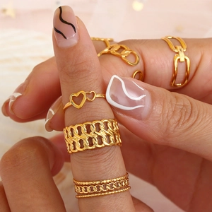 Close-up of gold plated stainless steel ring set with heart and chain designs on a model