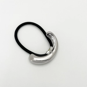 Detail of minimalist hair tie with silver curved metal piece on a black elastic band