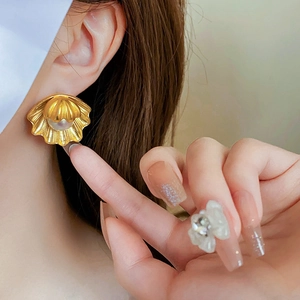 Detail of vintage gold shell earrings with pearl inlay shown on model's ear