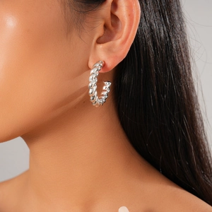 Close-up of model wearing a silver twisted C-shaped earring with geometric rope texture