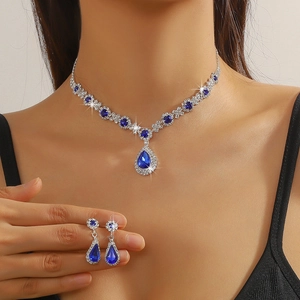 Detailed close-up of crystal necklace and teardrop earrings set on a female model