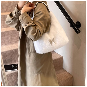 Detail of white faux fur shoulder bag featuring a silver metal butterfly ornament on a model