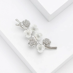 Detail of silver branch brooch with white and rhinestone flowers on white props