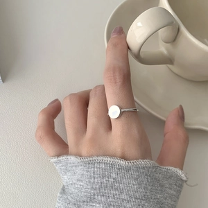 Detail of silver S925 ring with white round inlay on model hand with coffee cup