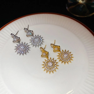 Detailed close-up of gold and silver Saturn star earrings with bright zircon inlay