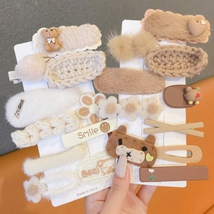 Close-up of cute plush bear and knitted flower hair clips set in warm brown tones