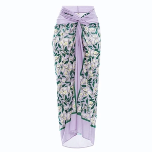 Détail d'un paréo violet à imprimé floral et feuilles avec un nœud latéral chic