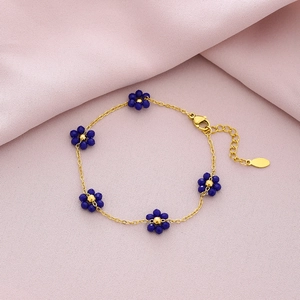 Detailed view of gold steel bracelet featuring five deep blue crystal flower charms