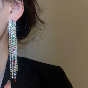 Close-up of elegant long tassel earrings with colorful square zircons on model ear