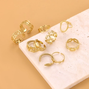 Detailed view of eight assorted gold-plated stainless steel rings on a stone display