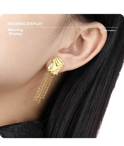 Close-up of a model wearing gold geometric tassel earrings with handmade forged texture